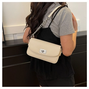Detail of cream crossbody bag featuring lychee texture leather and silver turn-lock clasp