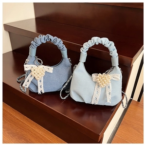 Detailed view of denim cloud bag with heart pearls, lace bows and ruched handle
