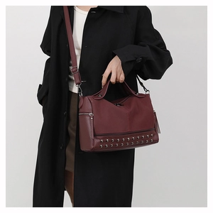 Close-up of burgundy rivet shoulder bag with litchi grain texture and metallic details