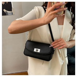 Close-up of black lychee grain leather shoulder bag with silver turn-lock clasp on model