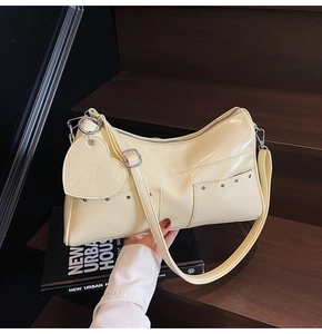 Dettaglio della borsa tote in pelle crema con borchie argentate e ciondolo a cuore