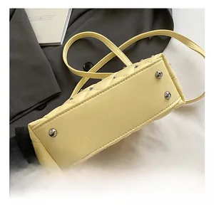 Close-up of light yellow quilted bag base with silver anti-wear metal studs