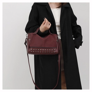 Detail of burgundy PU leather handbag featuring silver rivet studs and a long strap