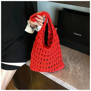 Detail of red hollow knit tote bag with honeycomb crochet pattern on marble surface