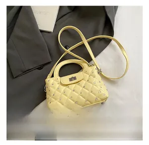 Detailed view of quilted faux leather texture with rhinestone studs on the pale yellow bag