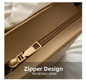 Detailed macro view of the premium golden metal zipper on a beige leather tote bag