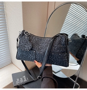 Dettaglio della borsa leopardata con rivetti e ciondolo a cuore in un set lifestyle