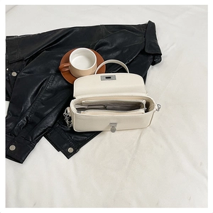 Detail of cream white leather bag showing dual zipper compartments and chain strap