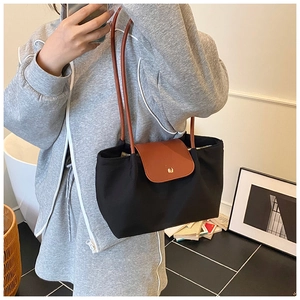 Detail of classic black fabric tote with brown leather handles and gold metal clasp
