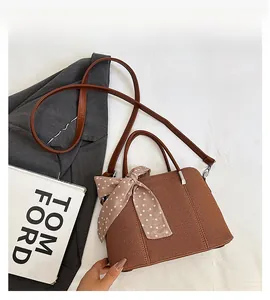 Détail du sac à bandoulière tissé marron foncé avec foulard à pois roses