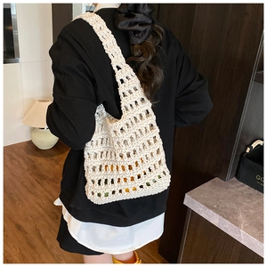 Detail of a beige crochet knit tote bag showing the hollow diamond mesh texture on model