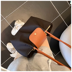 Detail of black nylon tote with brown leather handles and gold snap closure