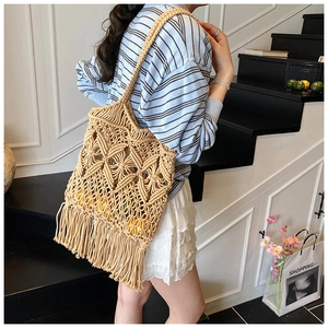 Détail d'un sac cabas en paille tissée avec pompons à franges et motif losanges