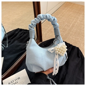 Detail of light blue denim handbag with ruffled handle, pearl heart and lace ribbon charm