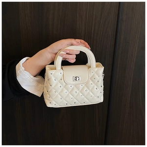 Detail of cream quilted handbag with silver rhinestone accents and metal turn-lock