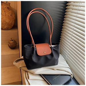 Detail of contrast handle and leather flap on large nylon tote bag with city aesthetic