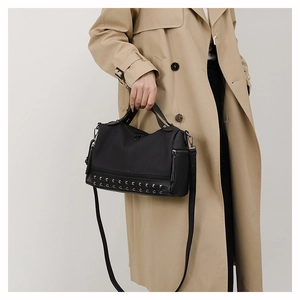 Detail of black PU leather handbag with silver studs worn with a khaki trench coat