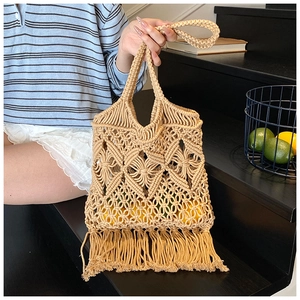 Détail du sac cabas bohème en paille évidée avec franges et texture tissée rustique