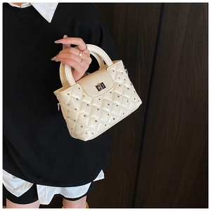Close-up of beige quilted handbag with sparkling rhinestone accents and silver twist lock