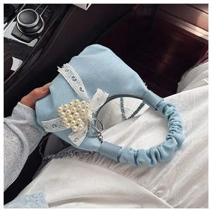 Detail of light blue denim handbag with pearl heart, lace bow and ruffled handle