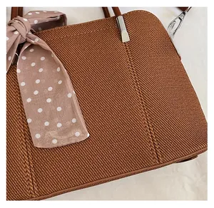 Détail d'un sac bandoulière marron tissé avec foulard rose à pois et métal argenté