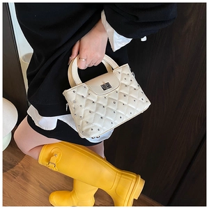 Detailed view of white quilted handbag with silver rivets and metal swivel lock