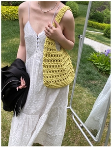Detail of hand-woven lemon yellow knit shoulder bag with hollow mesh design in outdoor set