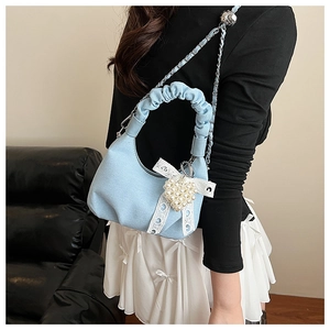 Detail of light blue denim bag featuring ruffled handle with pearl heart and lace bow