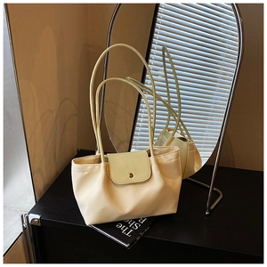 Close-up of cream and green tote bag featuring a round metal clasp on a textured surface