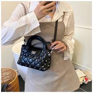 Detail of black quilted crossbody bag featuring silver rhinestones and metal twist lock