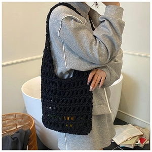 Detail view of black hollow knit tote bag with mesh pattern shown on a model