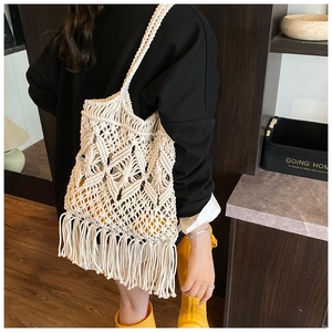 Détail d'un sac bandoulière en paille tissé avec motifs ajourés et longues franges