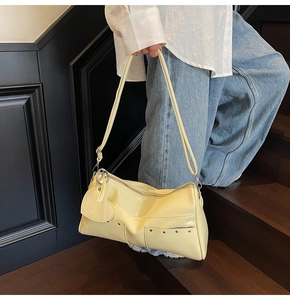 Dettaglio della borsa tote in pelle lucida gialla con borchie e ciondolo a cuore