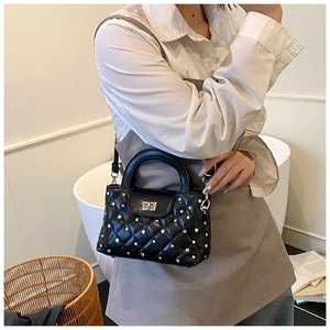 Close-up of black quilted crossbody bag with silver studs and metal twist lock