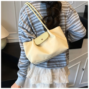 Detail view of the pale yellow shoulder bag with elegant pleated nylon material and metal buckle