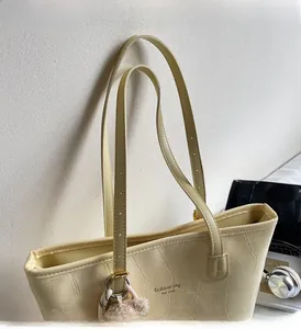 Detail der cremefarbenen Tote Bag mit Krokodilprägung und verstellbaren Riemen
