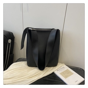 Close-up of minimalist black matte tote bag with wide straps and smooth leather texture