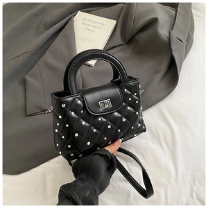 Detail of black quilted leather handbag with silver studs and metal twist lock closure
