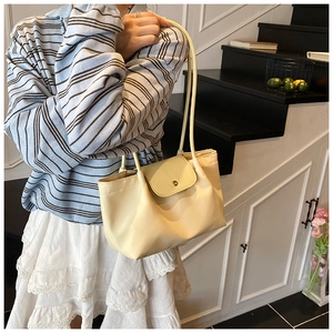 Detail of minimalist pale yellow handbag with magnetic flap closure and long straps