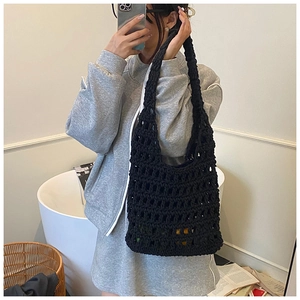 Detail of black crochet hollow-out knit tote bag used as a lightweight shoulder bag