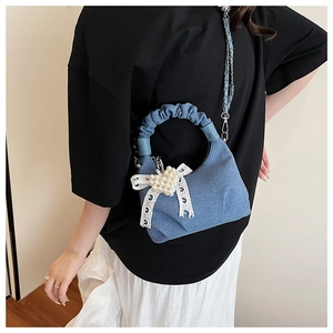 Detail of blue denim pleated bag with pearl heart and white lace bow decoration