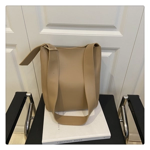 Detail of light khaki leather tote bag featuring adjustable strap and square metal buckle