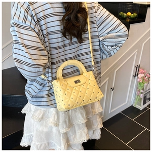 Close-up of yellow quilted handbag with shiny diamond studs and metal turn-lock detail
