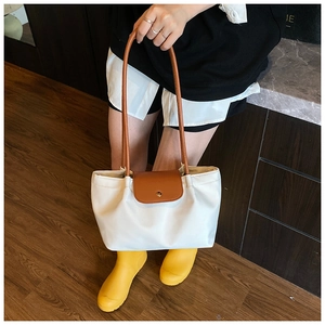 Detail of a large capacity contrast color tote bag with leather handles and metal clasp