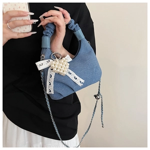 Close-up of blue denim hobo bag featuring lace bow, pearl heart and pleated handle