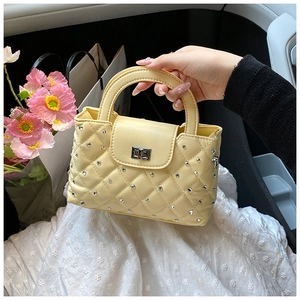 Yellow quilted handbag featuring silver stud accents and a metal turn-lock closure