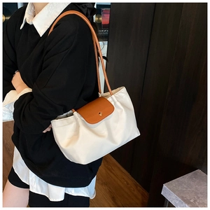 Detail of elegant contrast shoulder bag with brown leather flap and golden magnetic buckle