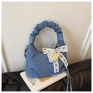 Detailed shot of a blue denim handbag with lace bow and pearl heart charm accessory