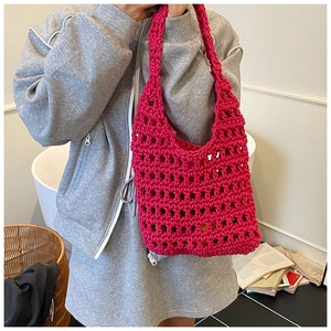 Macro detail of vibrant hot pink hand-knitted tote bag with thick woven hollow mesh texture