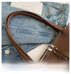 Close-up of brown leather tote bag dual zipper closure and white contrast stitching